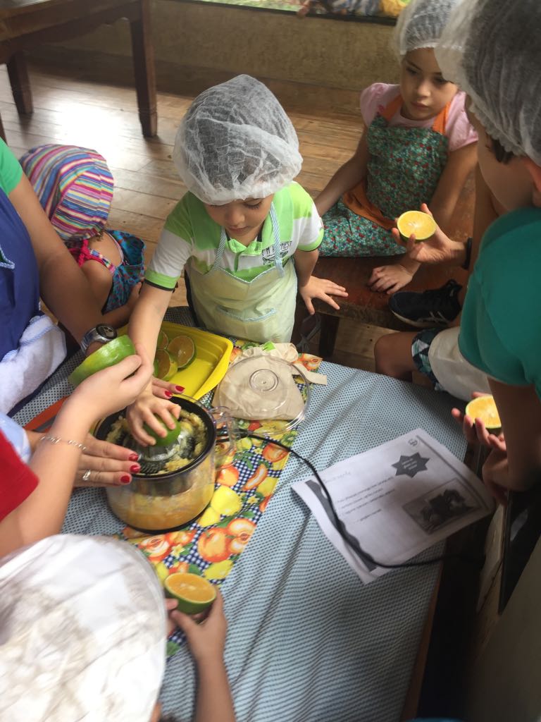 Crianças espremendo frutas durante oficina